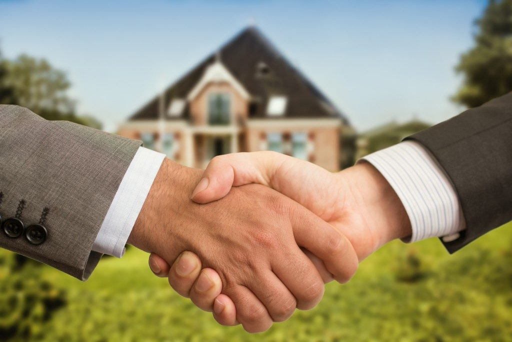 Photo of a handshake in front of a house