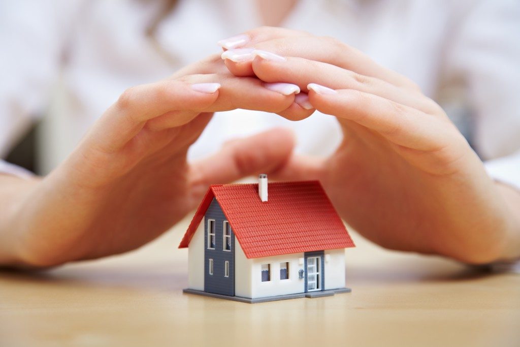 Woman hand placed above house model