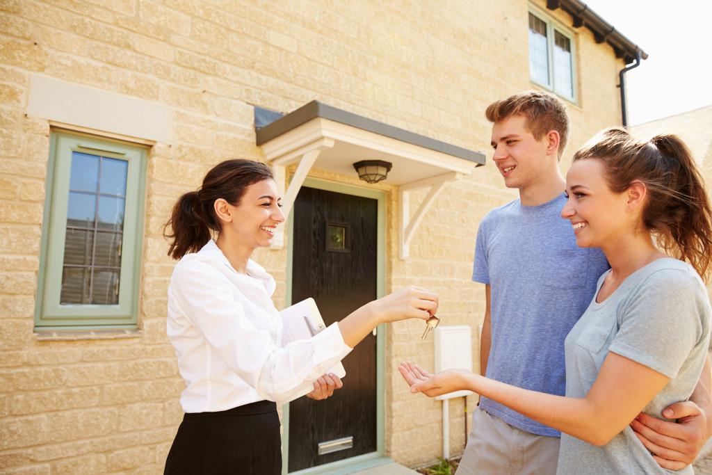 Real estate agent shaking hands with young adult buyers